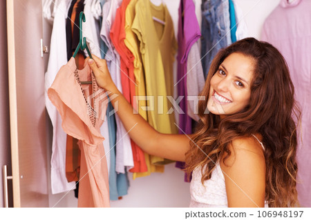 Should I wear this. Happy teen, portrait and fashion wardrobe girl in closet browsing for a cute party outfit. Beautiful and girly woman in bedroom cupboard happy and excited for her clothing choice. 106948197