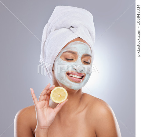 Mask, skincare and lemon with face of woman in studio for beauty, natural cosmetics and vitamin c. Self care, glow and spa with female model and citrus fruit on grey background for detox product 106948334