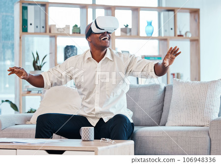 Virtual reality glasses, man and happy in house for cyber experience, metaverse interface or video game. Black male, VR and games in lounge for future innovation, ui technology and excited simulation Virtual reality glasses, man and happy in house for cyber experience, metaverse interface or video game. Black male, VR and games in lounge for future innovation, ui technology and excited simulation 106948336