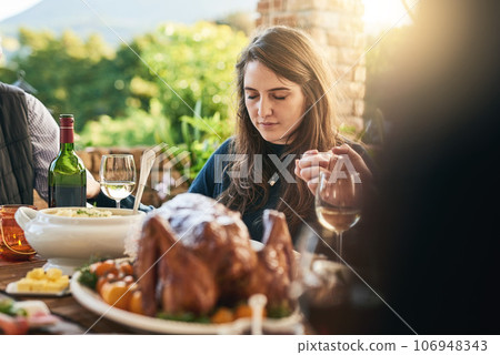 Family, food and prayer at table, hand holding and praying before sharing meal on patio, blessing and gratitude. Pray, hands and woman in thanksgiving grace before eating lunch with friends outdoor 106948343