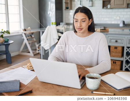 In working mode. Shot of a young woman working on a laptop while sitting at home. 106948398