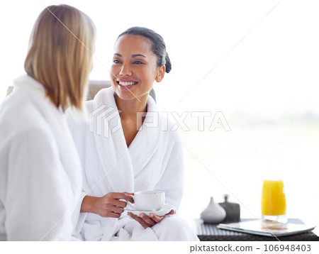 Enjoying some coffee between beauty treatments. Two young women having coffee in their bathrobes at the day spa. Enjoying some coffee between beauty treatments. Two young women having coffee in their bathrobes at the day spa. 106948403