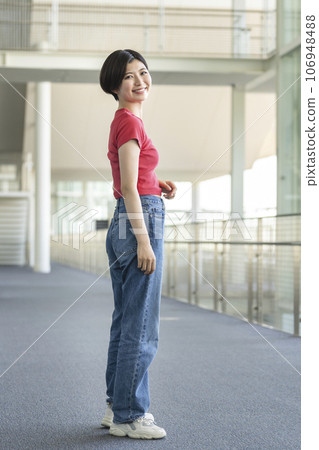 Full body portrait of a woman in her 20s smiling while looking at the camera 106948488