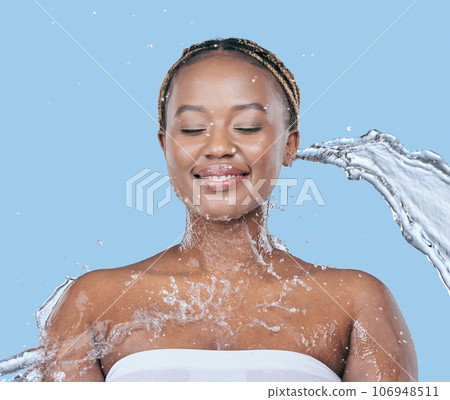 Let the water purify you. Studio shot of an attractive young woman being splashed with water against a blue background. Let the water purify you. Studio shot of an attractive young woman being splashed with water against a blue background. 106948511