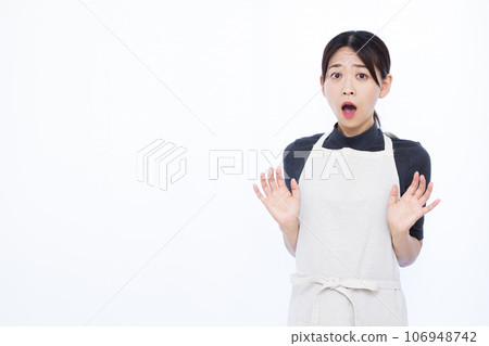 A housewife in her 30s looking surprised in front of a white background A housewife in her 30s looking surprised in front of a white background 106948742