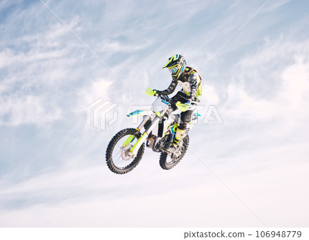 Blue sky, jump and man on motorbike in air for practice, training and extreme sports energy. Professional dirt biking speed challenge, off road adventure and danger at off road motorcycle competition 106948779