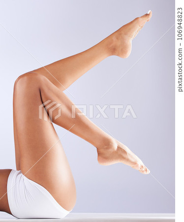 Skincare, body and woman legs with epilation, waxing and dermatology sitting in a studio. White background, laser and hair removal with self care, skin glow and wellness with feet pedicure and beauty 106948823