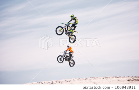 Sports, jump and people on motorcycle driving on sand, beach or training for a challenge, competition or desert rally. Dirt, motorbike and men in fearless extreme action, stunt or jumping in the air 106948911