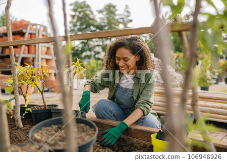 Professional woman garden worker transplants plants and takes care of flowerpots in botanic shop Professional woman garden worker transplants plants and takes care of flowerpots in botanic shop 106948926