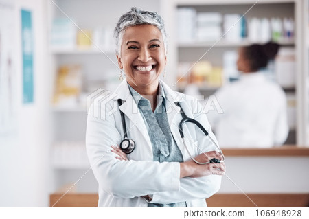 Mature, pharmacist or portrait of happy woman with arms crossed in healthcare clinic or drugstore. Proud, wellness or confident female doctor by pharmacy medication or medicine on shelf ready to help Mature, pharmacist or portrait of happy woman with arms crossed in healthcare clinic or drugstore. Proud, wellness or confident female doctor by pharmacy medication or medicine on shelf ready to help 106948928