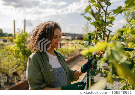 Cheerful female gardener takes care of plants while working in garden center 106948931