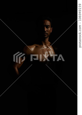 Topless, muscle and portrait man in dark background for fitness inspiration, beauty aesthetic or strong body. Shadow aesthetic, topless male model or body builder in creative studio with art lighting Topless, muscle and portrait man in dark background for fitness inspiration, beauty aesthetic or strong body. Shadow aesthetic, topless male model or body builder in creative studio with art lighting 106949159