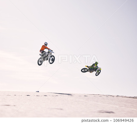 Dune, jump and men on motorbike together for practice, training and extreme sports energy in nature. Professional dirt biking challenge, friends and danger with motorcycle competition on desert hill. 106949426