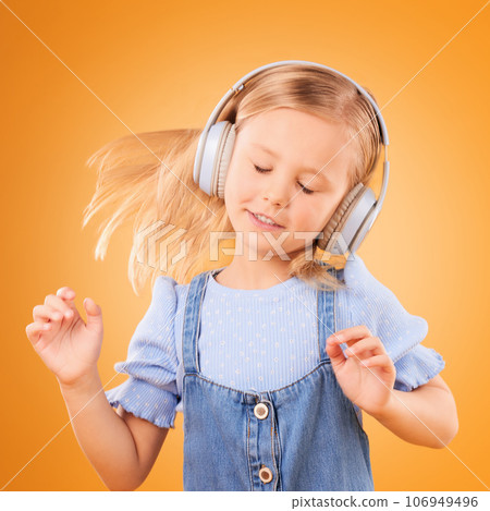 Headphones, dancing or child streaming music to relax with freedom in studio on orange background. Hair, moving or girl dancer listening to a radio song, sound or gospel on an online subscription 106949496