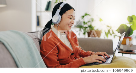 Laptop, headphones and asian woman on couch with work from home opportunity in online or website copywriting. Remote worker or person in china typing on her computer and listening to music at home 106949969