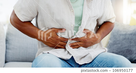 Man on a sofa with a tummy ache, pain or sickness while relaxing in the living room of his home. Illness, medical emergency and male with diarrhea, food poisoning or indigestion rubbing his stomach. Man on a sofa with a tummy ache, pain or sickness while relaxing in the living room of his home. Illness, medical emergency and male with diarrhea, food poisoning or indigestion rubbing his stomach. 106950177