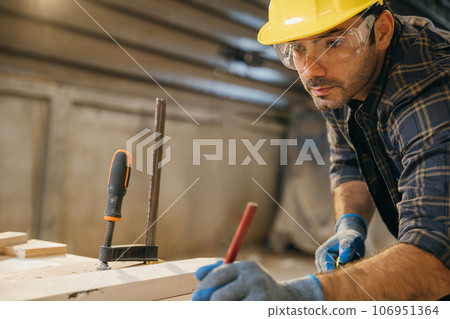 Carpenter man wear gloves during working using tape measure and pencil to make marks piece of wood board for cut on table saw at workshop or woodshop industry, woodwork, Happy Carpenter's Day Carpenter man wear gloves during working using tape measure and pencil to make marks piece of wood board for cut on table saw at workshop or woodshop industry, woodwork, Happy Carpenter's Day 106951364