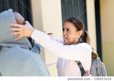 Strong woman using forceful blow in the eyes of rapist on street 106953028
