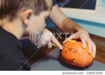 Children with father carving a traditional Jack lantern from pumpkin Children with father carving a traditional Jack lantern from pumpkin 106953089