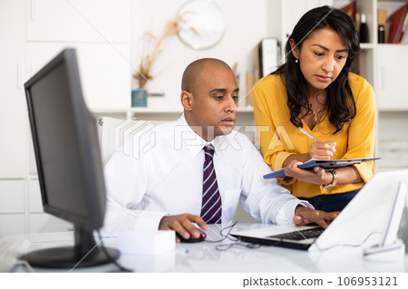 Focused female assistant writing down tasks of boss in office 106953121