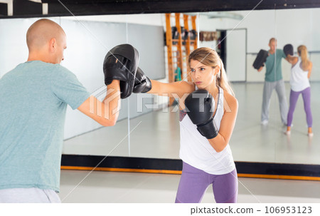 Adult man is training with woman and punching gloves in box gym Adult man is training with woman and punching gloves in box gym 106953123