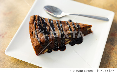 Sweet delicate triangular piece of chocolate-nut pie, poured with liquid chocolate, served on plate Sweet delicate triangular piece of chocolate-nut pie, poured with liquid chocolate, served on plate 106953127