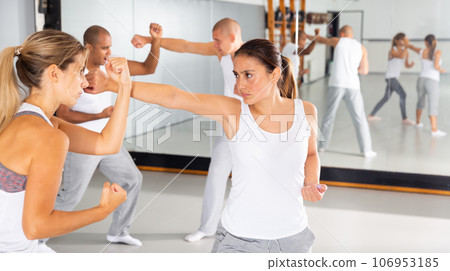 Hispanic woman practicing self defense moves with female partner 106953185
