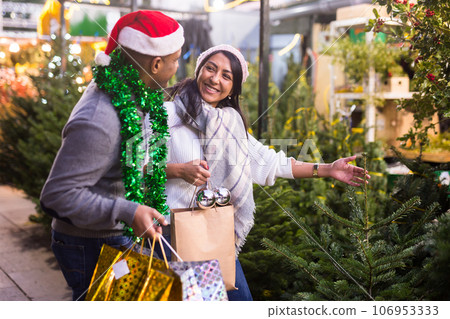 Family couple choosing christmas tree at christmas fair 106953333