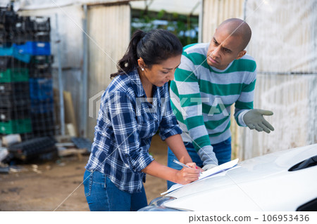 Couple of farmers discussing papers near car on backyard Couple of farmers discussing papers near car on backyard 106953436