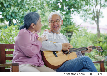 Happy Asian senior couple elderly man playing guitar while his wife singing together outdoors at home, Activity family health care, Enjoying lifestyle during retirement life having fun of senior older Happy Asian senior couple elderly man playing guitar while his wife singing together outdoors at home, Activity family health care, Enjoying lifestyle during retirement life having fun of senior older 106953760