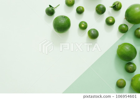 On the green background, green color of limes and kumquats are decorated. Creative background with blank space for design and copy space. Top view, flat lay 106954601