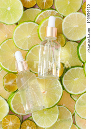 Top view of two unlabeled serum bottles placed on top of line and kumquat slices. Creative scenes for product advertising. Dropper bottles without label for design 106954610