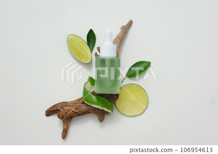 Natural vitamin C skincare product with fresh lime slices decorated with green leaves and dry twig on white background. Mockup scene for advertising and space for design 106954613