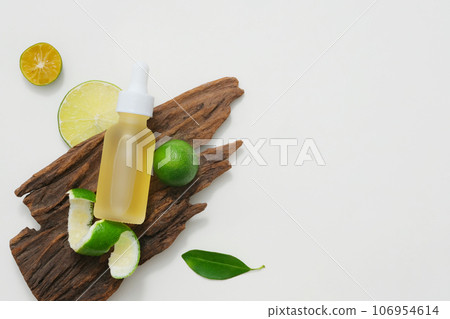 On a dry wood branch, a unlabeled serum bottles displayed with slices of lime and kumquat. Blank space for the presentation product or copy space for text. Minimal concept 106954614