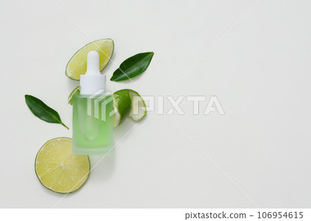 Background for the presentation of cosmetic products extracted from lime. A dropper bottle without label mockup for design. Space for text. Top view 106954615