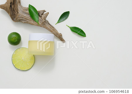 A yellow cosmetic jar decorated on white background with kumquat, lime and dry branch. Minimalist concept for advertising and branding product. Copy space 106954618