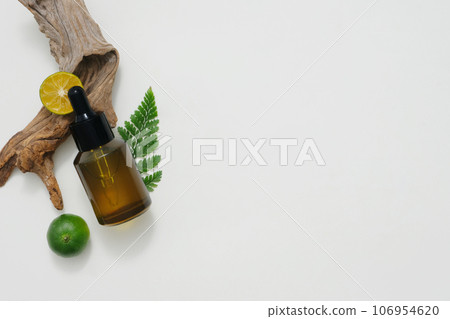 On a white background, an amber bottle displayed with kumquat slices. Space for cosmetic product mockup. Product and promotion concept for advertising. Natural ingredient rich in vitamin C 106954620