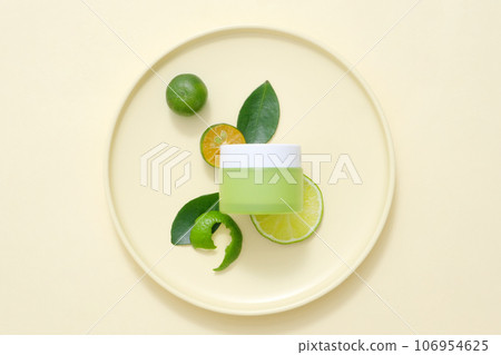 Minimalist concept for advertising cosmetic with natural ingredient rich in vitamin C. A green cream jar unlabeled mockup for design, decorated with kumquats on beige background 106954625