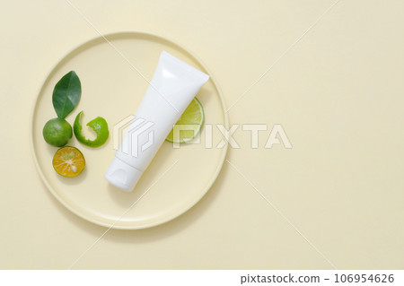 Plastic bottle displayed with kumquat slices and green leaves on beige background. Minimal background with copy space for cosmetics, business branding and product presentation Plastic bottle displayed with kumquat slices and green leaves on beige background. Minimal background with copy space for cosmetics, business branding and product presentation 106954626
