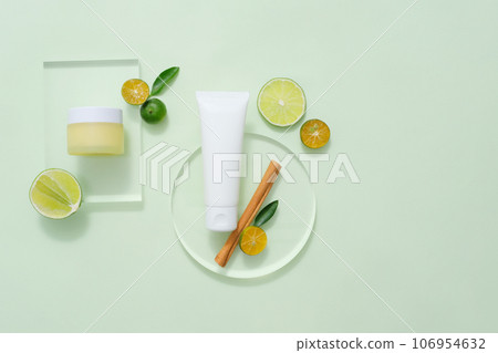 On the pastel background, set of cosmetic bottles displayed with slices of lime and kumquat, cinnamon stick decorated. Mock up for package design. Natural cosmetic concept 106954632