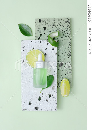 Minimalist concept for advertising cosmetic of lime extract. A dropper bottle displayed on brick podiums on green background. Top view, space for design 106954641