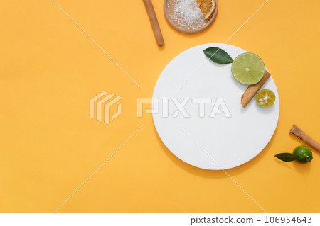 Natural ingredients used to produce essential oils are displayed on an orange background. Cinnamon, lemon and kumquat all produce very fragrant and popular essential oils 106954643