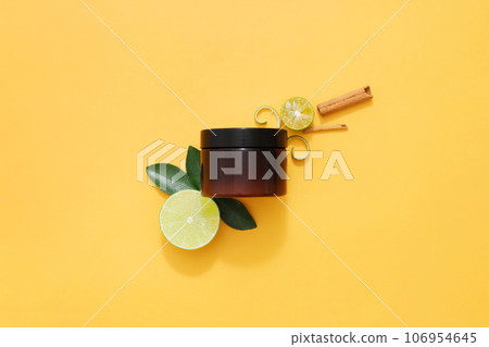 An amber jar without label decorated with lime, kumquat and cinnamon stick on orange background. Mockup for design, organic cosmetics, beauty products concept 106954645