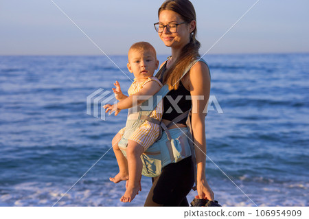 Young mother with her baby boy on the beach at sunset. Happy family. Young mother with her baby boy on the beach at sunset. Happy family. 106954909