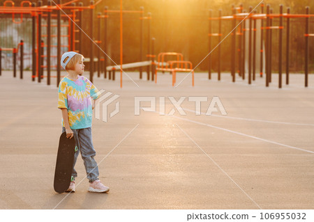 Fashionable child girl in casual clothes and jeans stands with skateboard 106955032