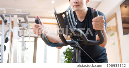 A man exercising on an exercise bike at a sports gym (health/diet) 106955112