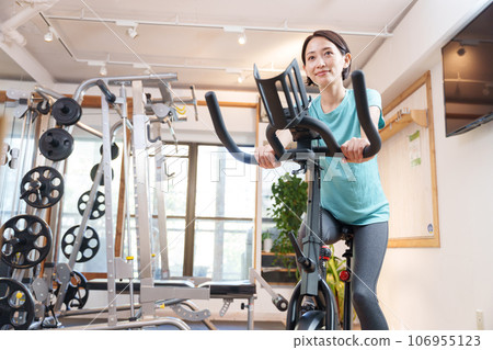 一位女士在健身房騎健身車鍛煉（健康/飲食） 106955123