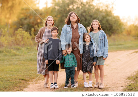 A large friendly family walks in a field in the summer 106955538