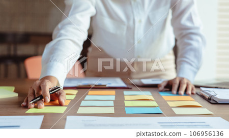 Businesswoman writing data in sticky notes on table to sharing ideas about strategy of new business Businesswoman writing data in sticky notes on table to sharing ideas about strategy of new business 106956136