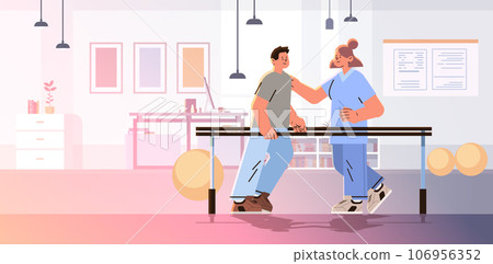 doctor helps patient after injury or medical operation during physio therapy man having physical rehabilitation in modern fitness studio 106956352